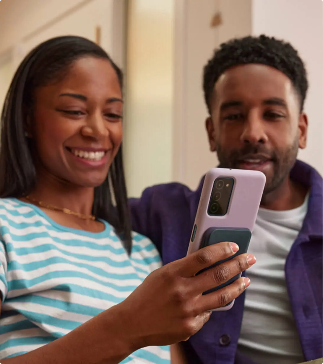happy black couple sitting reviewing their finances on their smartphone