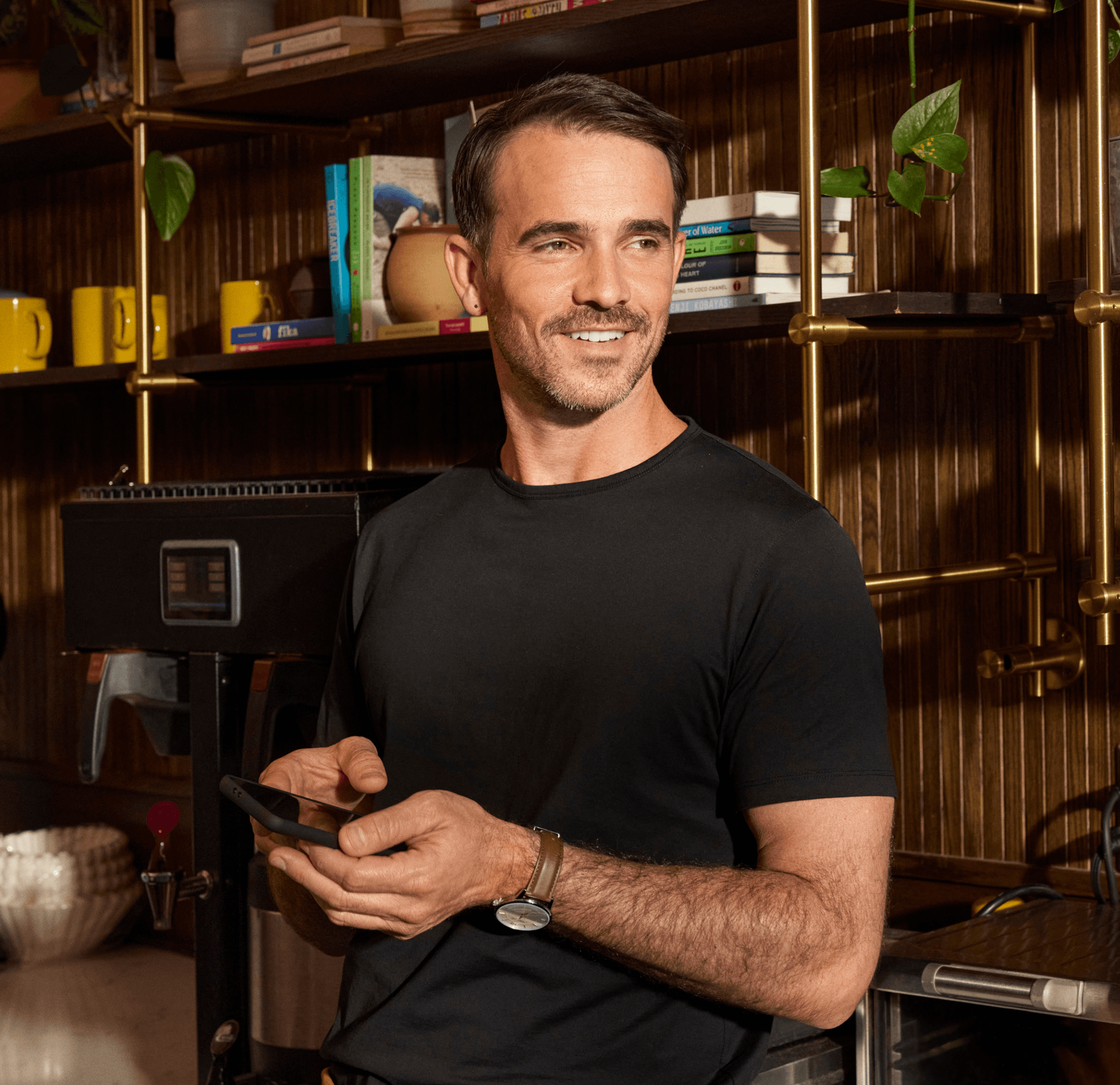 man in black shirt using free mobile banking in coffee shop in front of books